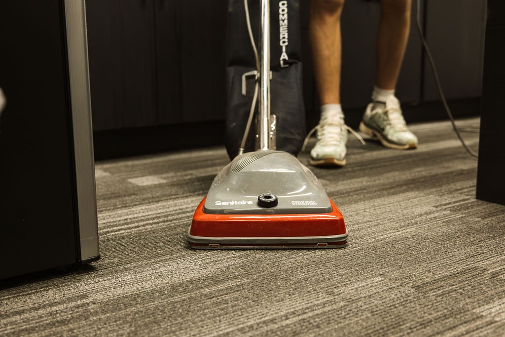 Close-up of an upright vacuum cleaning low-pile carpet